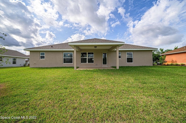 rear view of house with a patio and a lawn