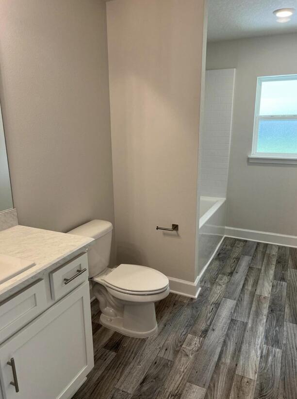 full bathroom with shower / bathtub combination, hardwood / wood-style floors, vanity, and toilet