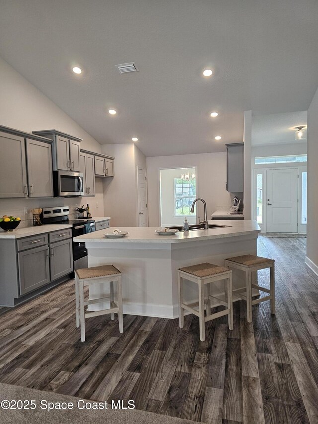 920 Lyons Cir NW, Palm Bay, FL 32907 - kitchen featuring stainless steel appliances, gray cabinets, dark wood-style flooring, a breakfast bar, and a sink