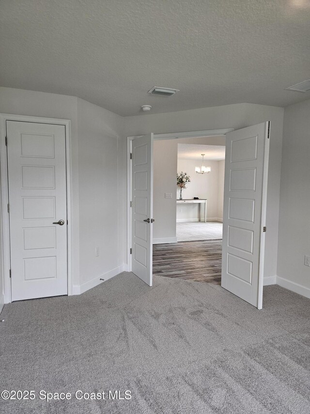 920 Lyons Cir NW, Palm Bay, FL 32907 - unfurnished bedroom featuring carpet floors, a chandelier, baseboards, and a textured ceiling