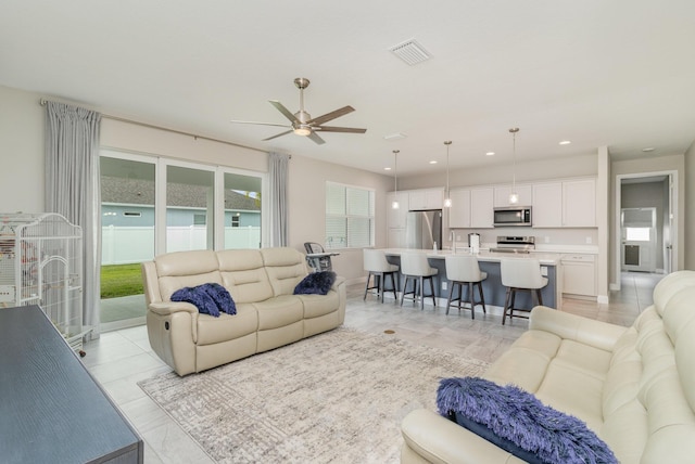 tiled living room with ceiling fan and sink