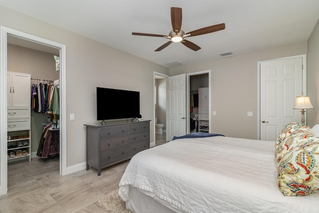 bedroom with ceiling fan, a walk in closet, ensuite bath, and a closet