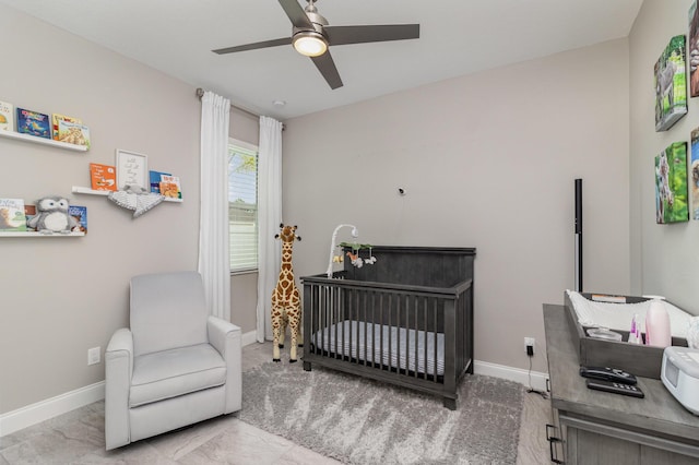 bedroom featuring ceiling fan and a crib