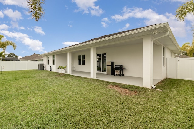 rear view of property featuring central AC unit, a patio, and a lawn