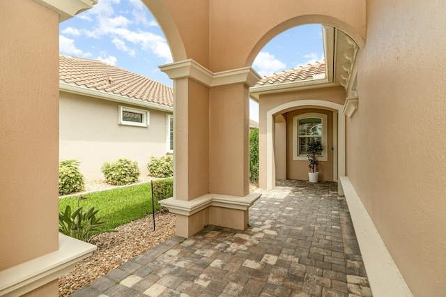 view of exterior entry with a tile roof and stucco siding