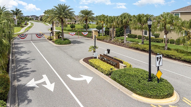 view of road featuring street lighting, a gated entry, and curbs