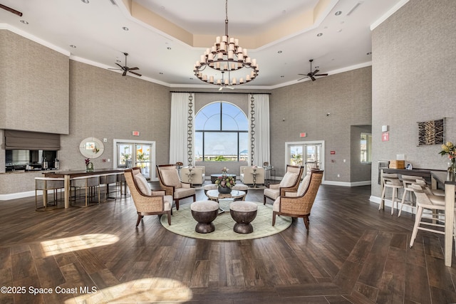 living area with ceiling fan, a tray ceiling, wood-type flooring, and baseboards