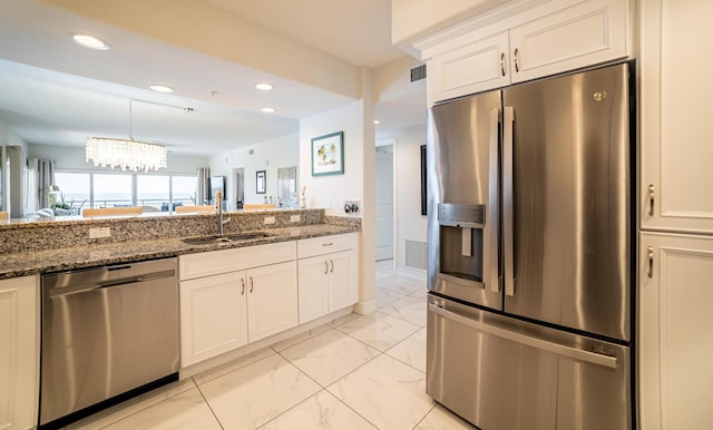 kitchen with appliances with stainless steel finishes, white cabinetry, dark stone countertops, and sink