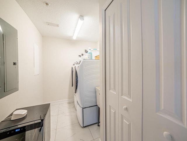 clothes washing area featuring washer and dryer, a textured ceiling, and electric panel