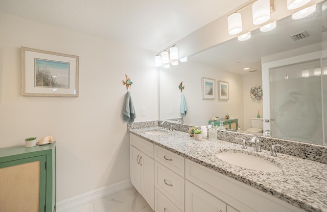 bathroom with vanity, toilet, and a textured ceiling