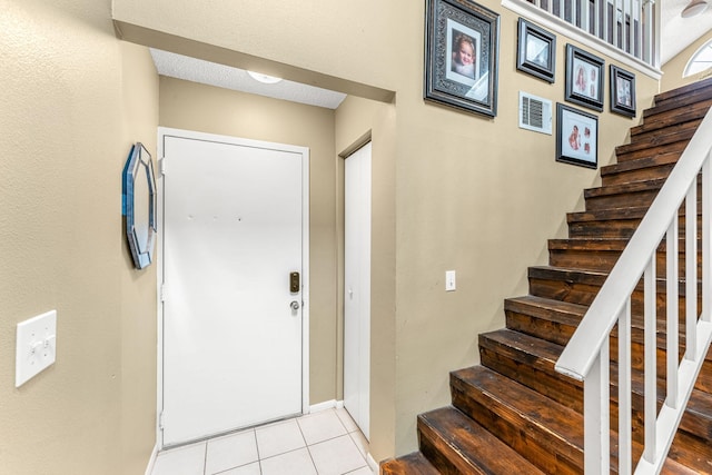 foyer entrance featuring a textured ceiling and light tile patterned floors