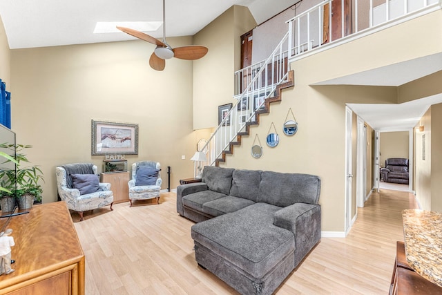 living room with ceiling fan, a skylight, high vaulted ceiling, and hardwood / wood-style flooring