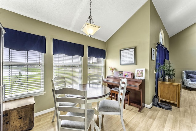 dining room with lofted ceiling, a textured ceiling, and light hardwood / wood-style floors