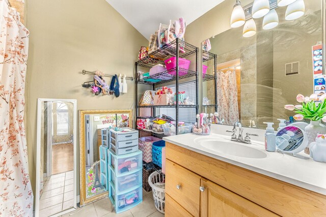 bathroom with lofted ceiling, tile patterned floors, and vanity