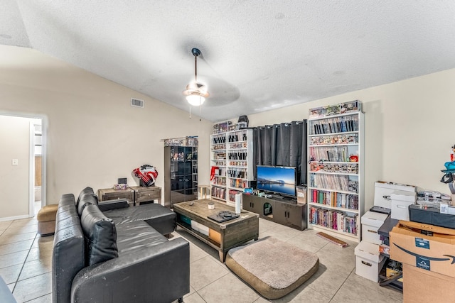 living room featuring a textured ceiling, ceiling fan, lofted ceiling, and light tile patterned floors