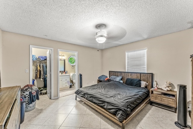 bedroom featuring a spacious closet, a closet, a textured ceiling, light tile patterned flooring, and ceiling fan