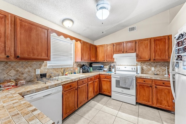 kitchen with decorative backsplash, white appliances, light tile patterned floors, and a textured ceiling