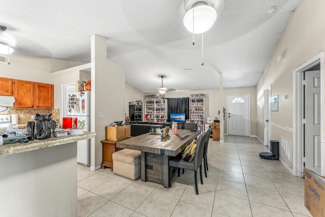 kitchen with vaulted ceiling, decorative backsplash, light tile patterned flooring, white fridge, and ceiling fan