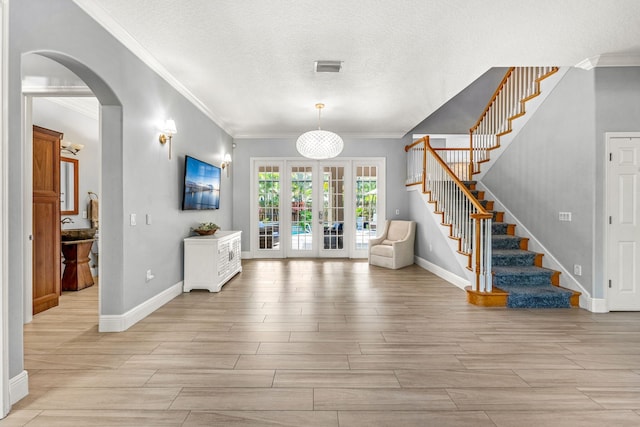 entryway featuring a textured ceiling, french doors, and crown molding