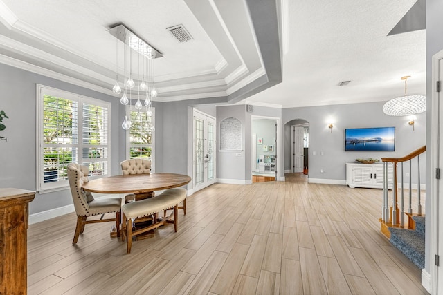 dining space featuring a tray ceiling, crown molding, and light hardwood / wood-style flooring