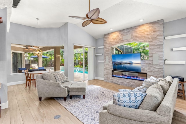 living room featuring lofted ceiling, ceiling fan with notable chandelier, hardwood / wood-style flooring, and a fireplace