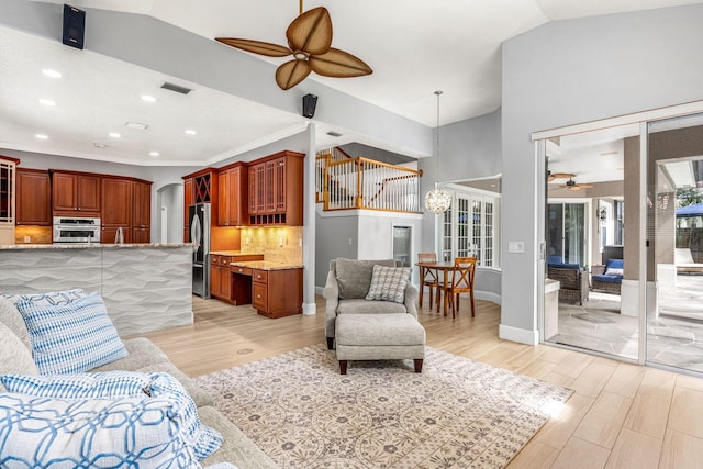 living room with lofted ceiling, ceiling fan, and light hardwood / wood-style flooring