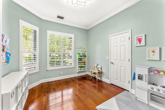 recreation room featuring a textured ceiling, hardwood / wood-style floors, and crown molding