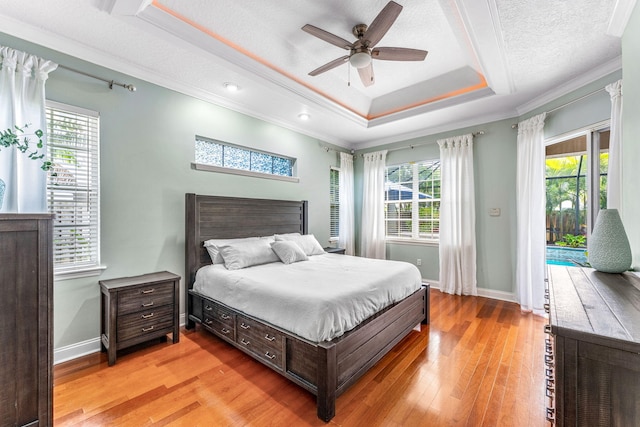 bedroom with a raised ceiling, light hardwood / wood-style floors, ceiling fan, access to exterior, and a textured ceiling