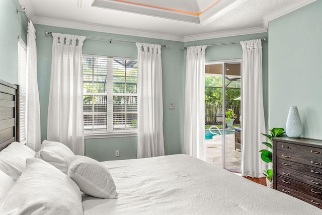 bedroom with ornamental molding, access to outside, and a tray ceiling