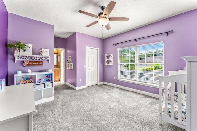 bedroom with a nursery area, ceiling fan, a closet, and carpet