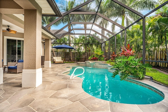 view of swimming pool featuring ceiling fan, a patio, glass enclosure, and an in ground hot tub