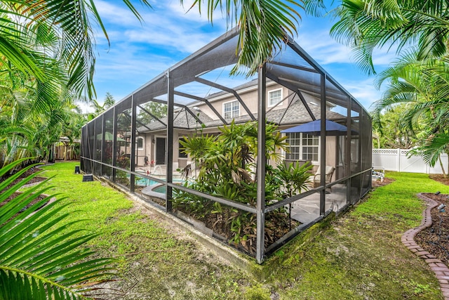 exterior space featuring a fenced in pool, a yard, and glass enclosure