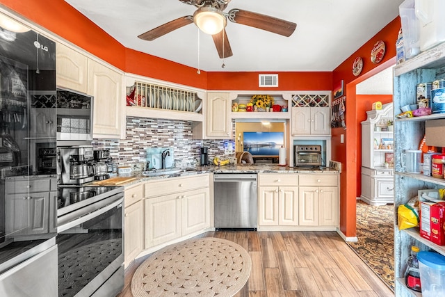 kitchen with appliances with stainless steel finishes, stone counters, sink, light hardwood / wood-style flooring, and tasteful backsplash