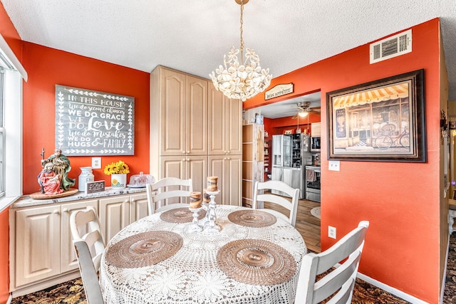 dining space with a textured ceiling and a notable chandelier