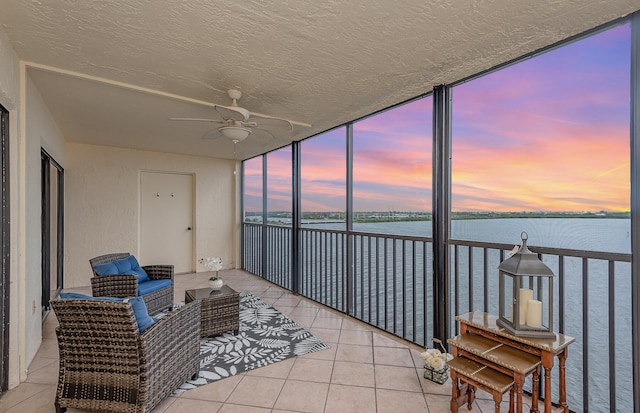 sunroom / solarium featuring a water view and ceiling fan