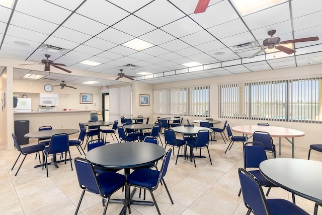 tiled dining space with a drop ceiling and ceiling fan