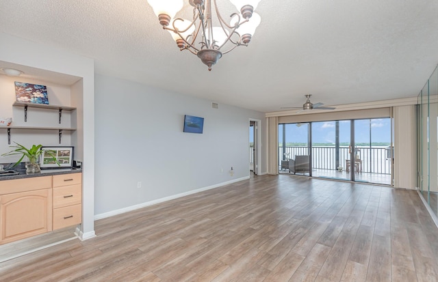 unfurnished living room with light hardwood / wood-style flooring, a textured ceiling, and ceiling fan with notable chandelier