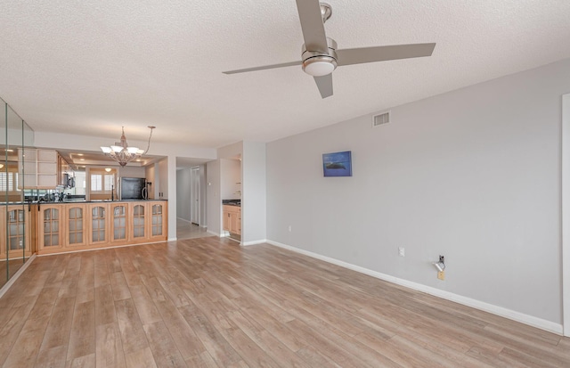 unfurnished living room featuring light wood-type flooring, ceiling fan with notable chandelier, and a textured ceiling