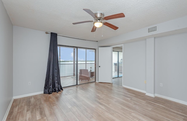 spare room with ceiling fan, light hardwood / wood-style flooring, and a textured ceiling