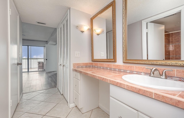 bathroom with tile patterned floors, vanity, and a textured ceiling