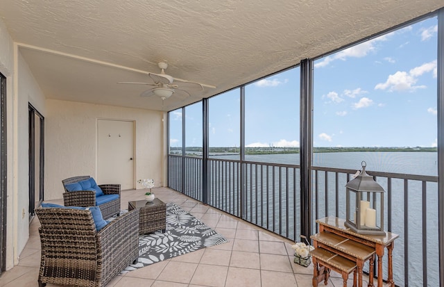 sunroom with a water view and ceiling fan