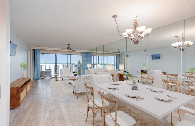 dining area with light wood-style flooring, a textured ceiling, and ceiling fan with notable chandelier