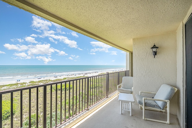 balcony featuring a water view and a beach view