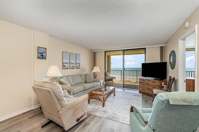 1860 N Atlantic Ave Unit 604, Cocoa Beach, FL 32931 - living area featuring a textured ceiling, a healthy amount of sunlight, and light wood-style flooring
