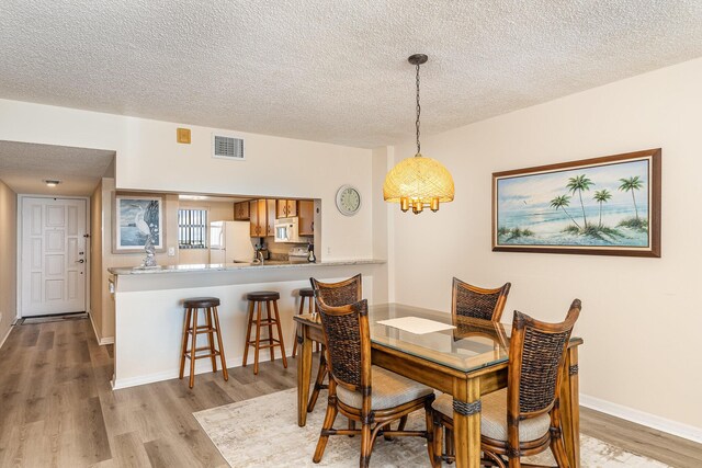 1860 N Atlantic Ave Unit 604, Cocoa Beach, FL 32931 - dining room featuring baseboards, visible vents, light wood-type flooring, and a textured ceiling