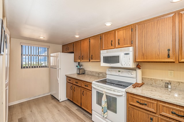 kitchen featuring light hardwood / wood-style floors, light stone countertops, and white appliances