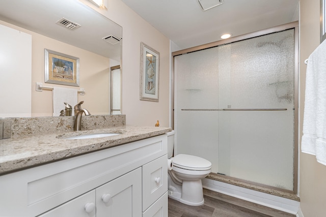 bathroom with wood-type flooring, a shower with door, toilet, and vanity