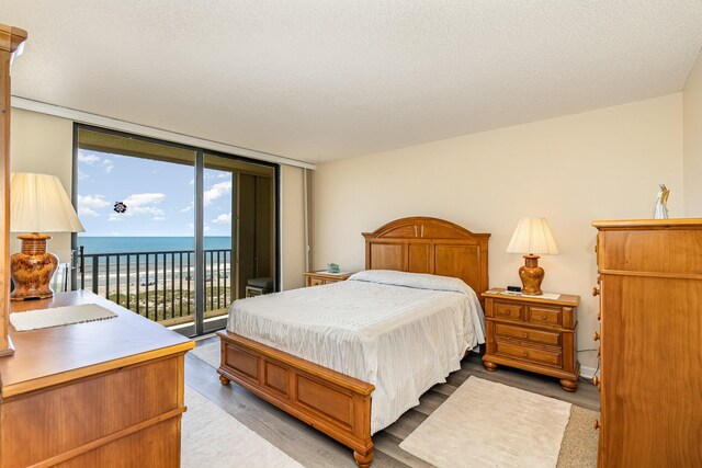1860 N Atlantic Ave Unit 604, Cocoa Beach, FL 32931 - bedroom featuring access to exterior, a textured ceiling, wood finished floors, and expansive windows
