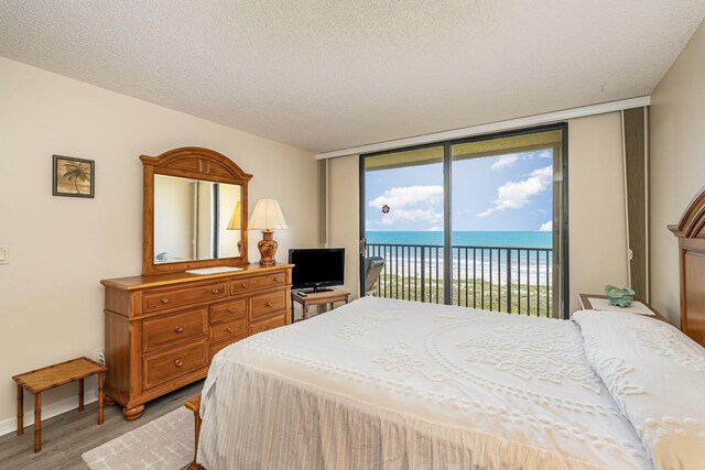 1860 N Atlantic Ave Unit 604, Cocoa Beach, FL 32931 - bedroom with light wood-style floors, access to exterior, baseboards, a textured ceiling, and floor to ceiling windows