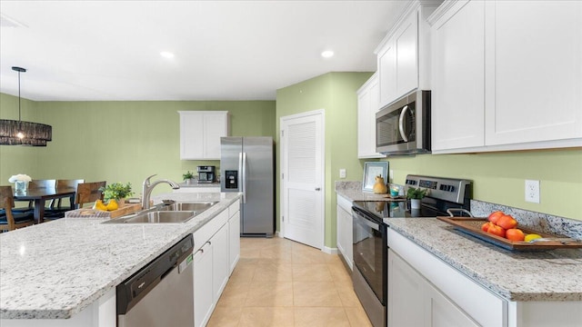 kitchen featuring pendant lighting, sink, white cabinetry, stainless steel appliances, and a center island with sink